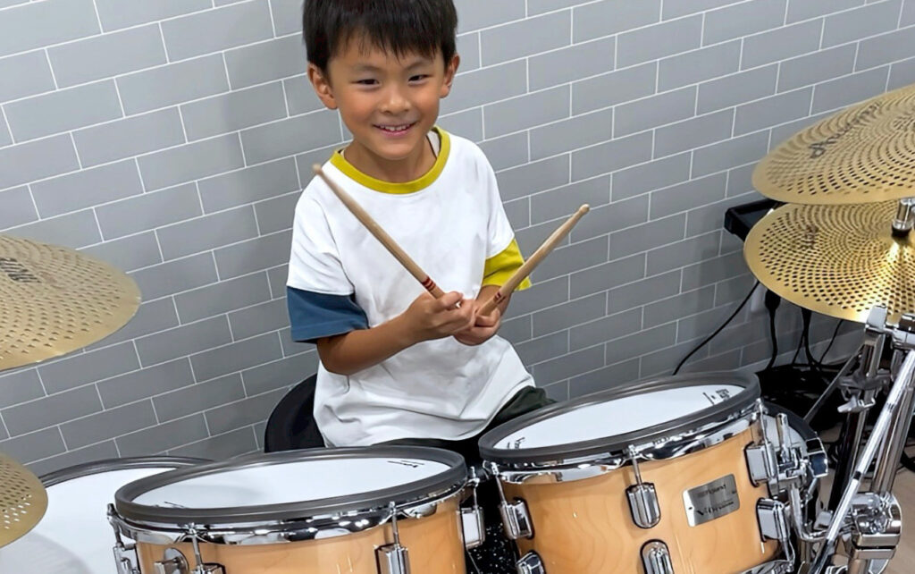 子供がドラムを叩いている画像